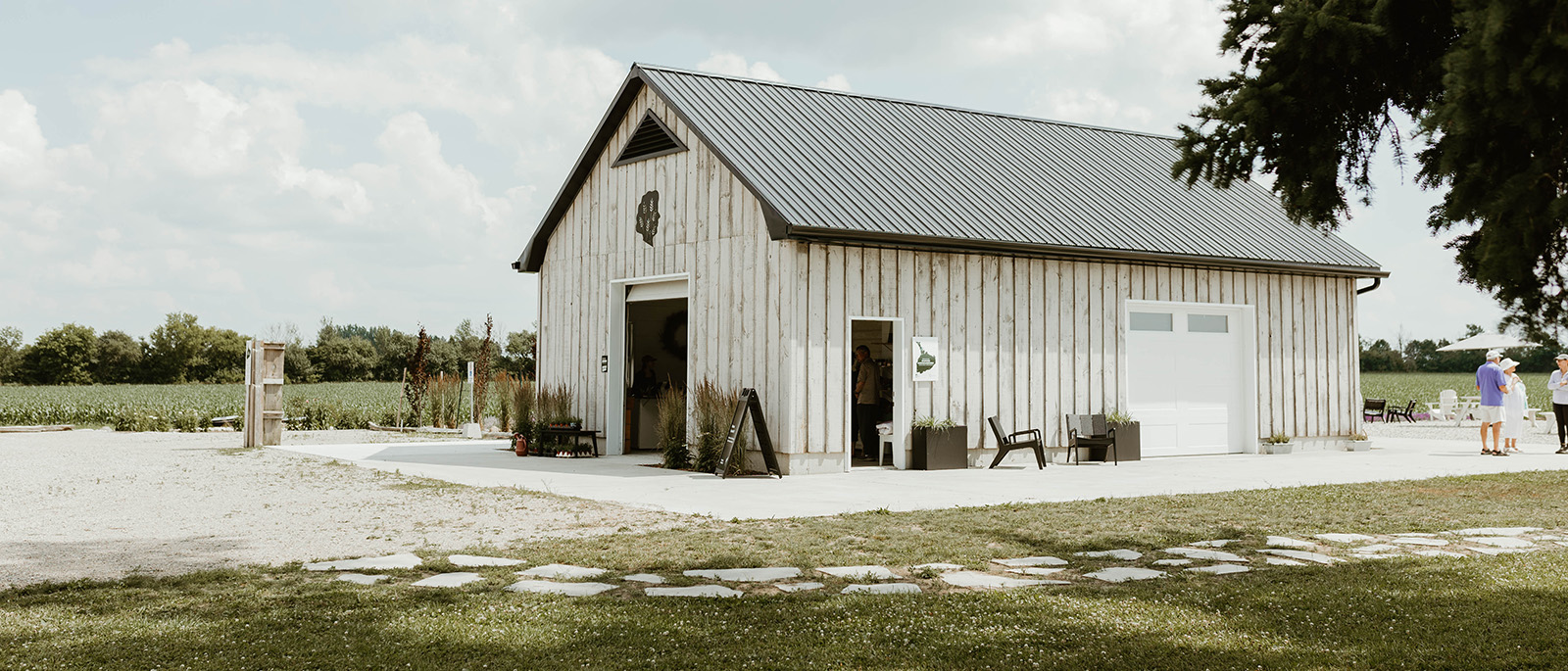 Photograph of a white barn surrounded by dormant lavender fields with three people standing in the distance.