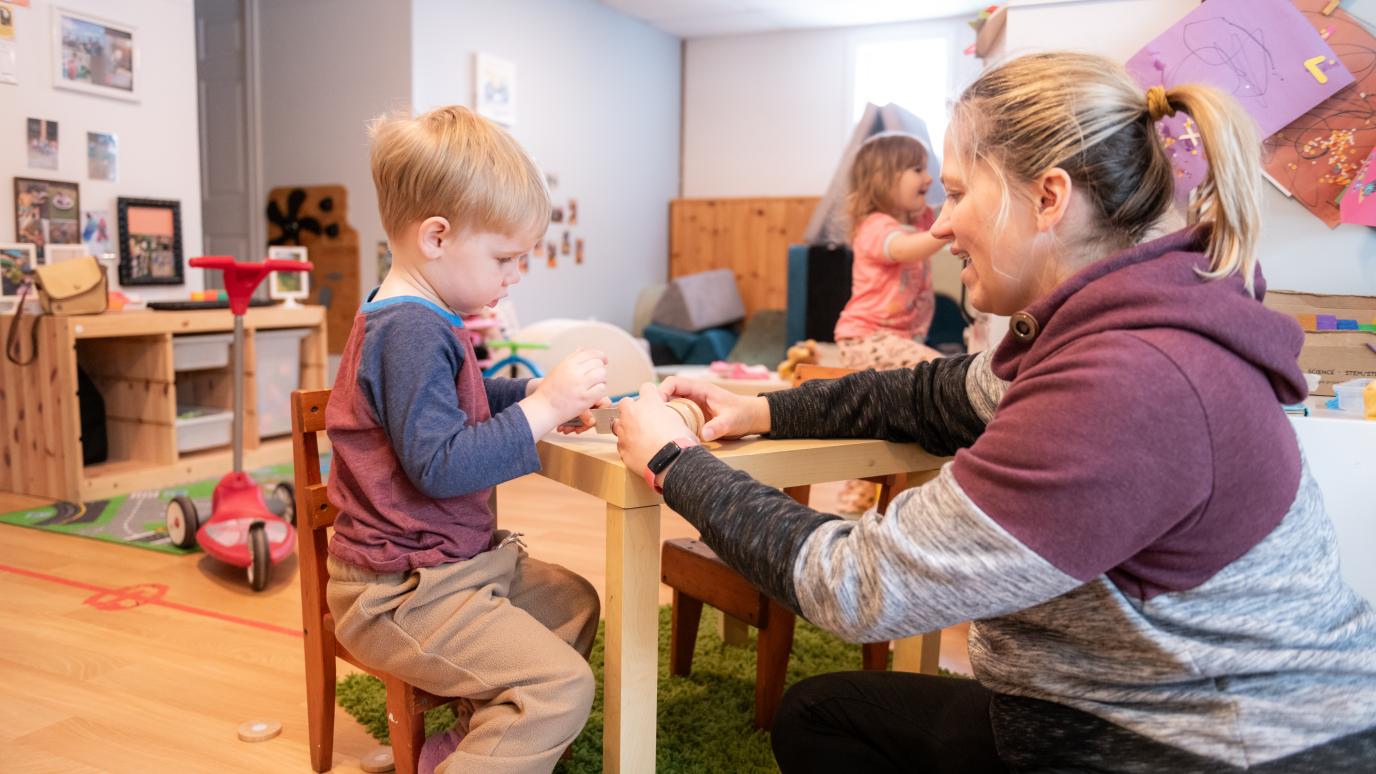 Child Care provider helping young boy at table