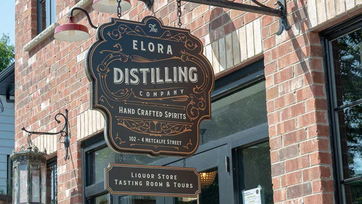 Decorative sign for Elora Distilling mounted on the front of their red brick building 