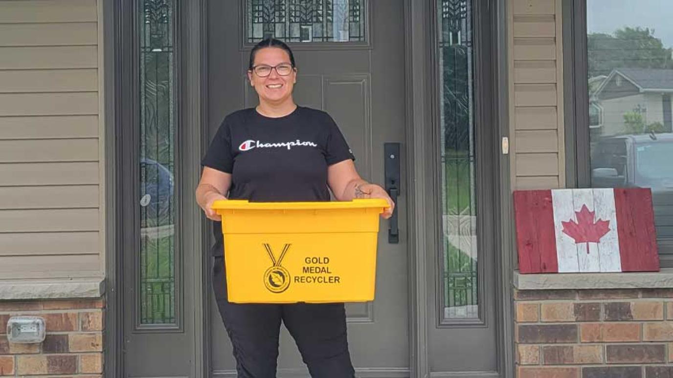 Woman smiling holding her new gold recycling bin