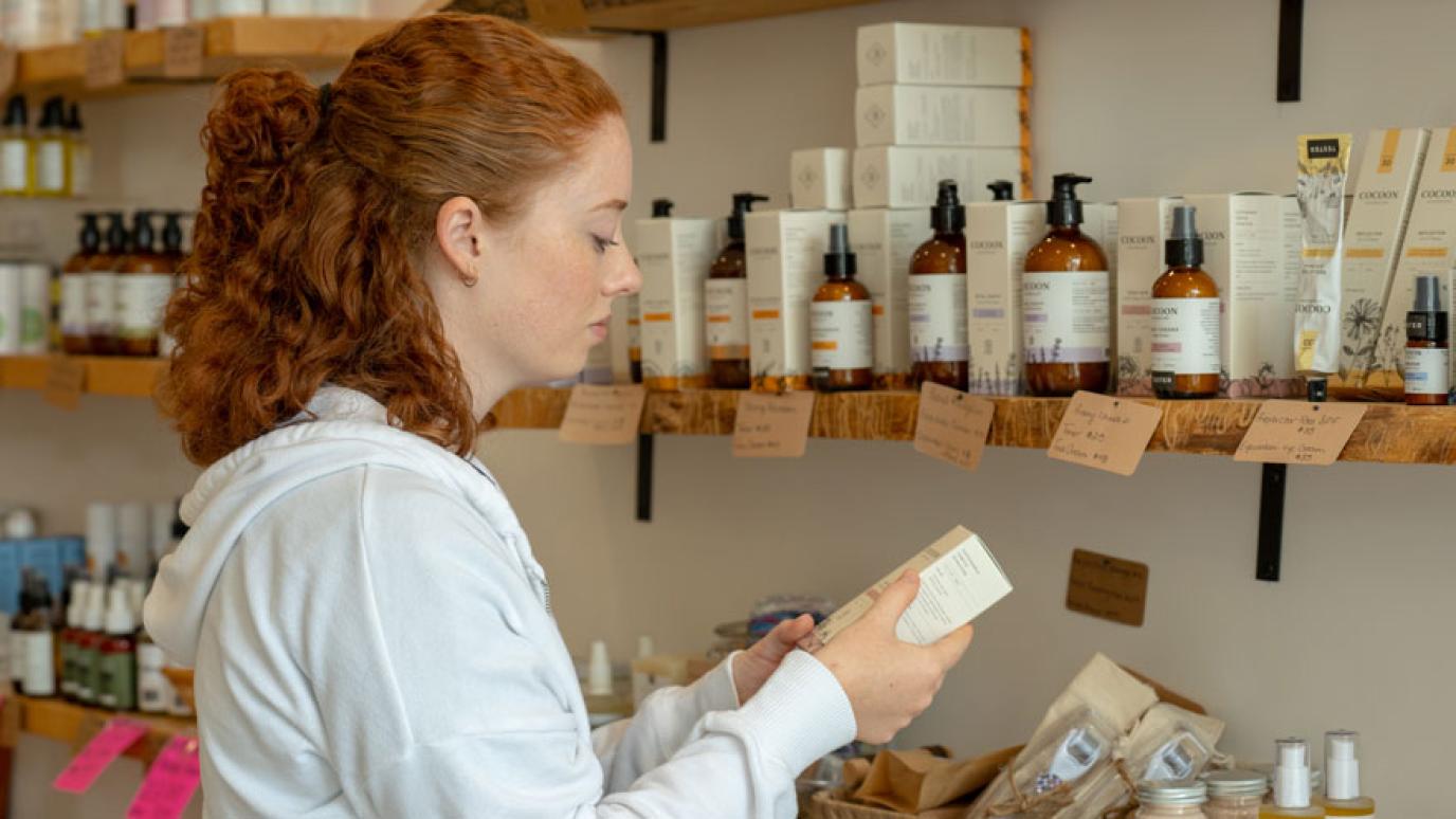 Young woman perusing a wall of natural skin care products at the Eco Den in Mount Forest.