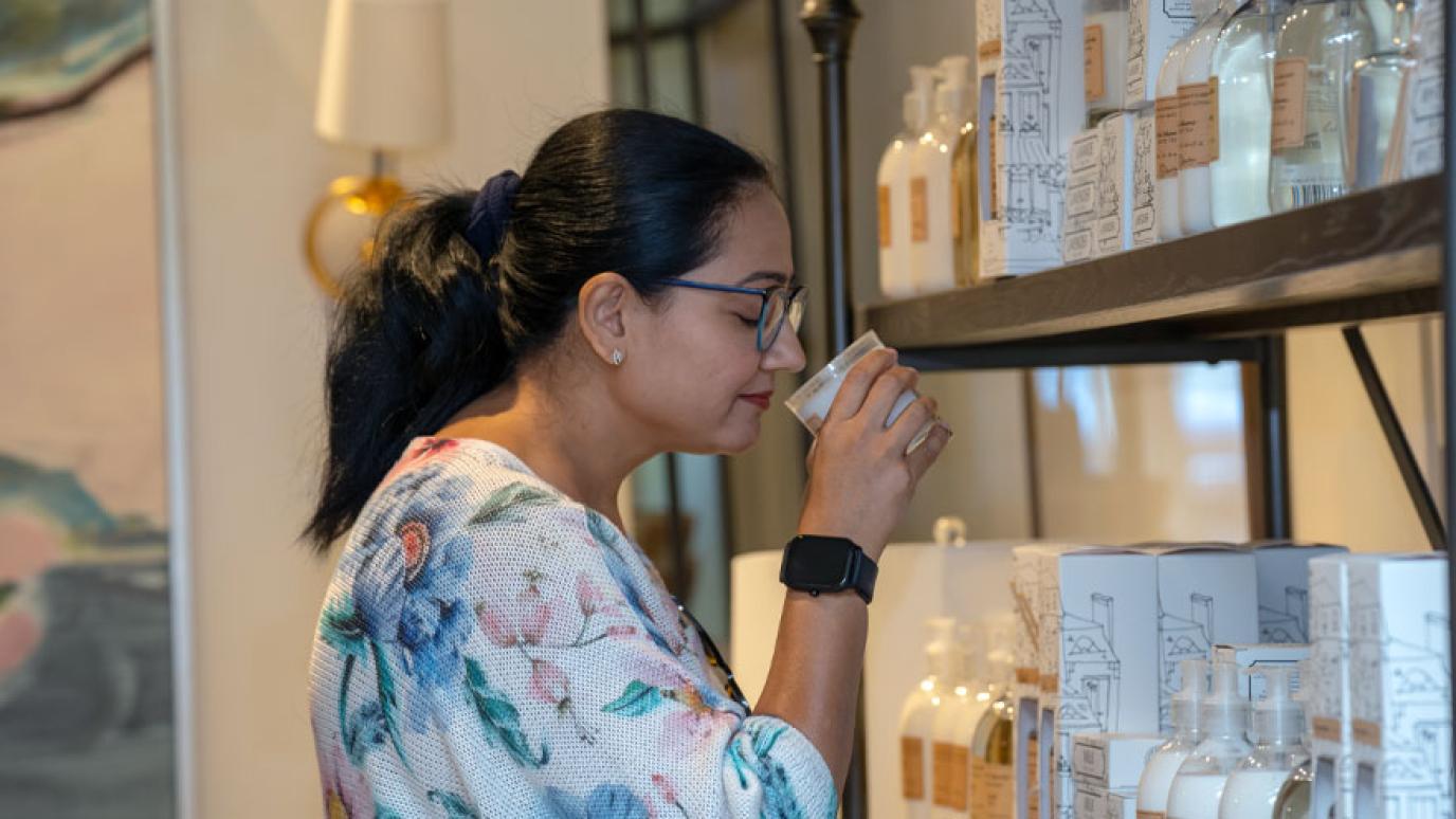 A woman delights in the smell of a scented candle for sale