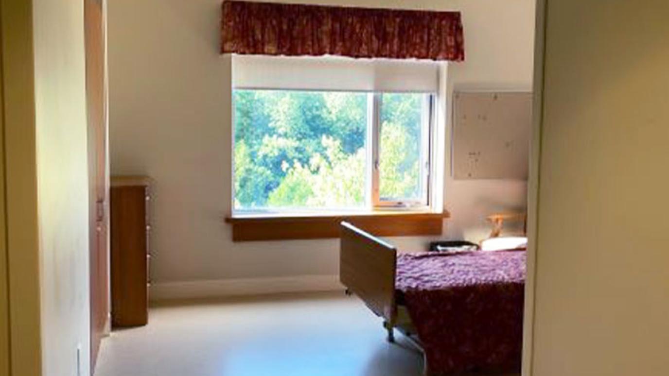 Single room with a bed, dresser, and lovely garden view from the window