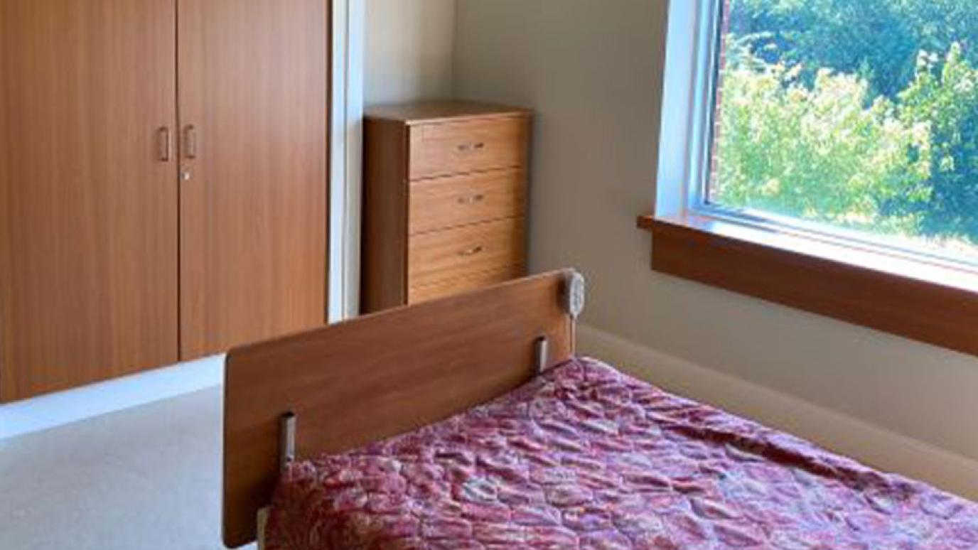 Single room with a bed, dresser, and lovely garden view from the window