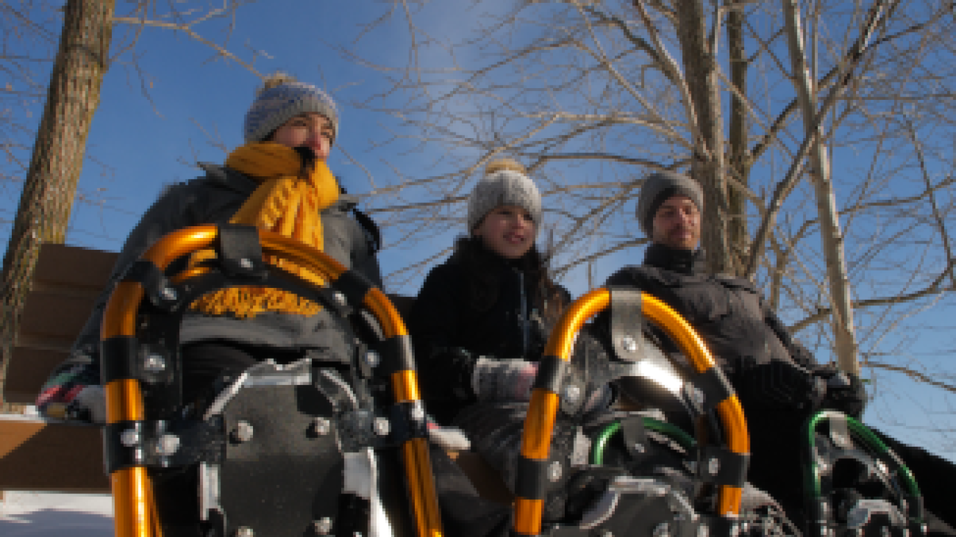 three people sitting with snowshoes