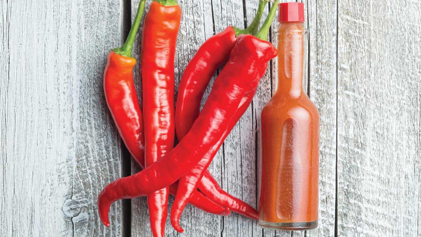 hot sauce bottle beside red hot peppers