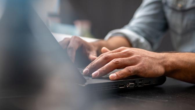 Close-up of mans hands using laptop.