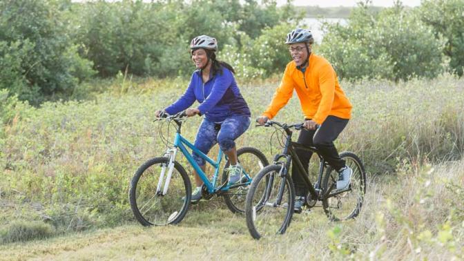 A man and woman biking through a rural field