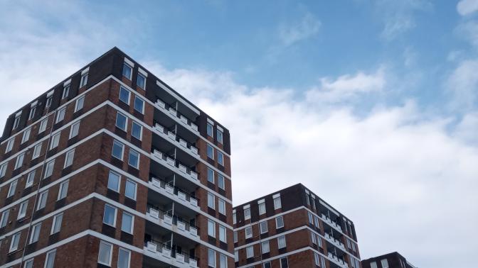 three apartment buildings with a bright blue sky behind them. 