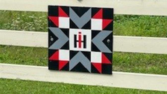 white farm gate fence with square artwork piece replicating a quilt patch