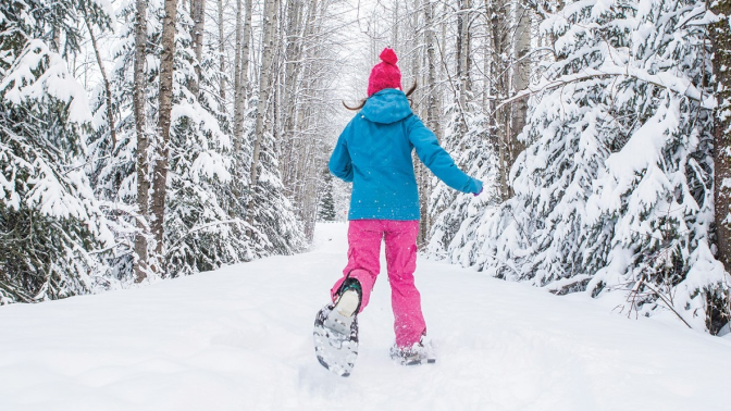 person running through snow on a trail with snowshoes