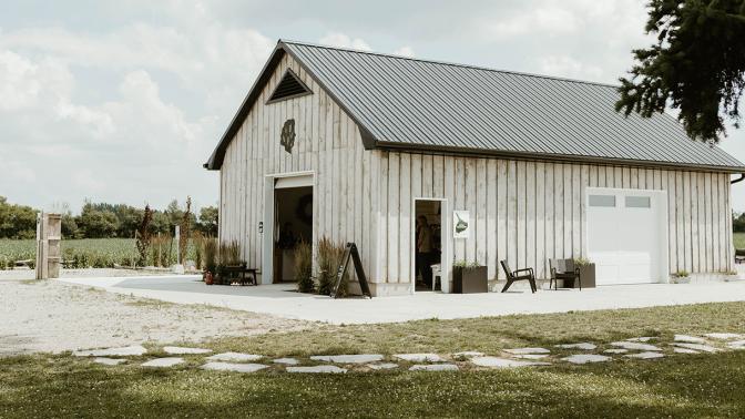 Photograph of a white barn surrounded by dormant lavender fields with three people standing in the distance.