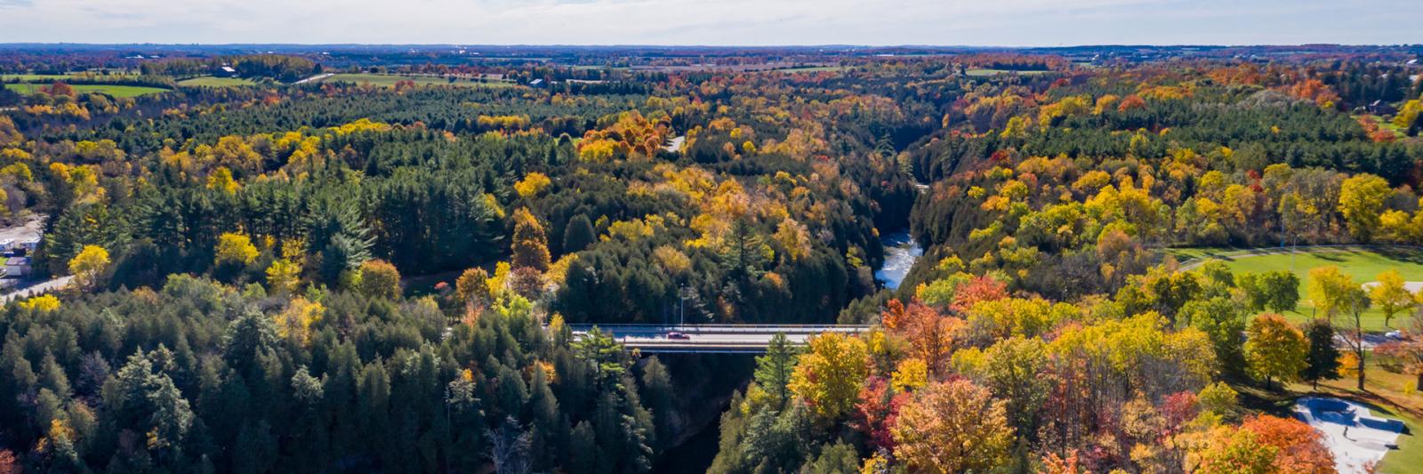 Birds eye view of the Elora area on a clear Fall day, showcasing the Grand River amidst the Fall foliage.
