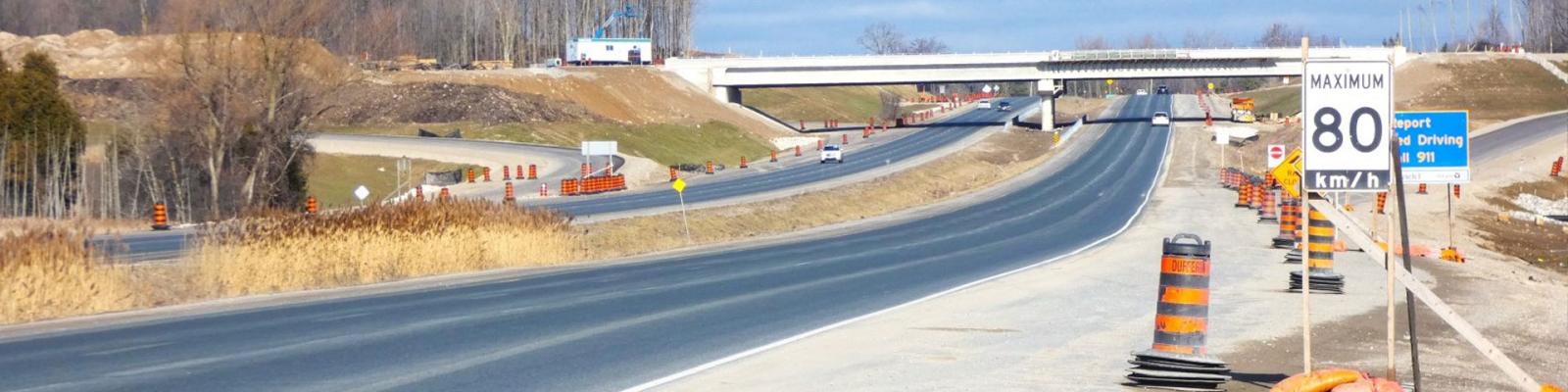 Stretch of Hwy in puslinch with construction pylons, an overpass in the distance and an 80 km/hour speed limit sign