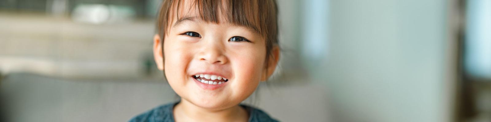 Close up of a toddler with a big smile on her face
