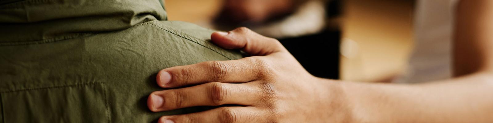 Hand touching someones shoulder in an act of comfort