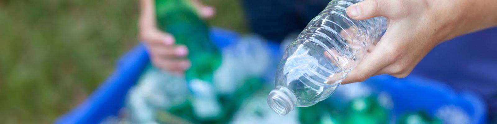 Crop of someone sorting plastic bottles to go in the blue bin 