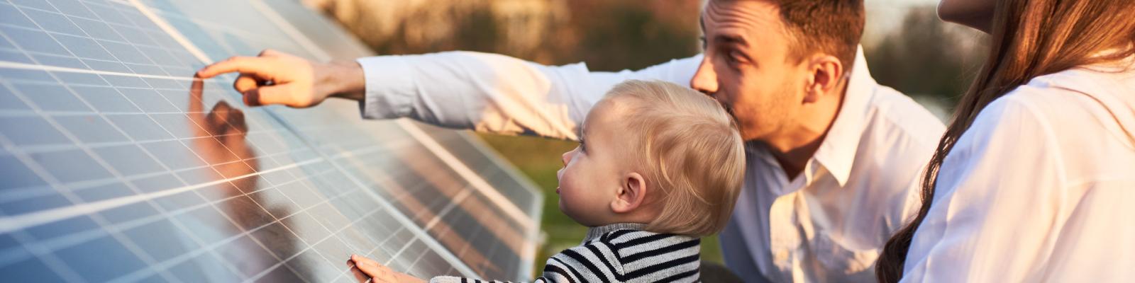 Father pointing to details on a solar panel showing his his toddler son how they work