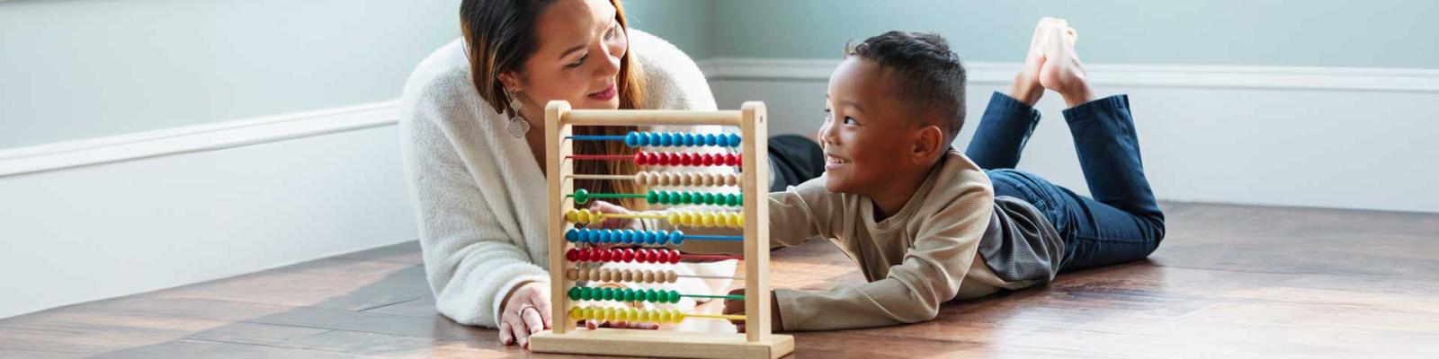 Young multiracial boy with early child educator using abacus