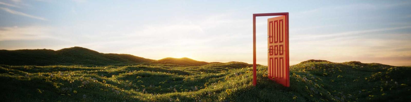 An open door frame stands in the middle of rolling hills