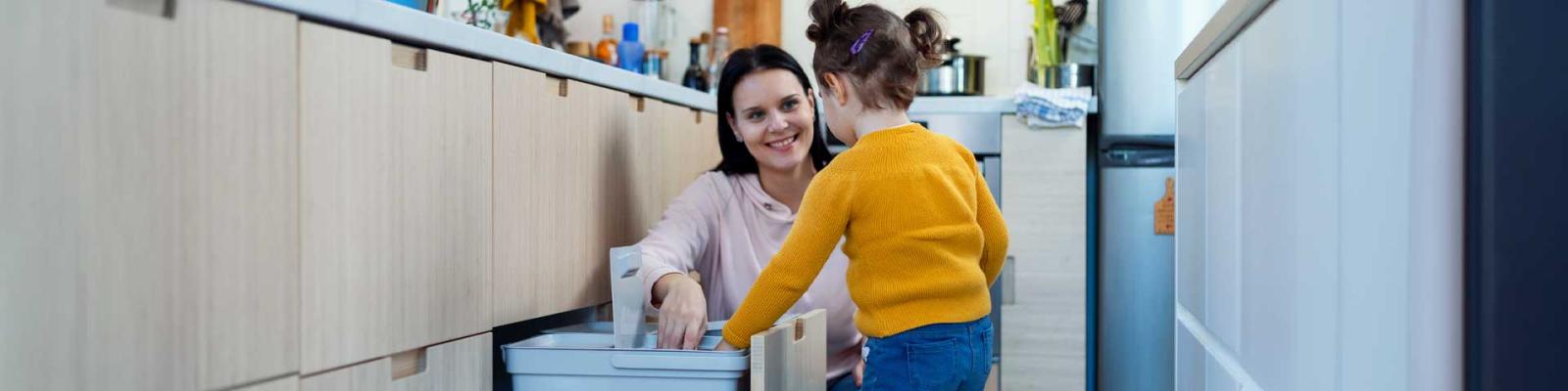 Mother and daughter sorting recycling in their apartment kitchen