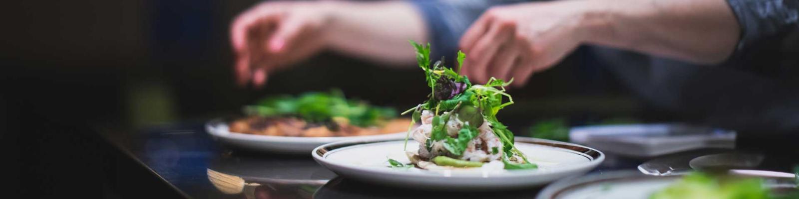 Chefs hands plating food dishes at a fine dining restaurant