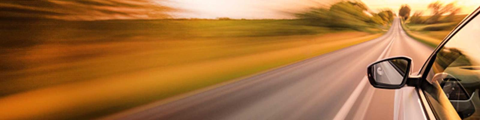 View of driver side of car zooming through an open road. 