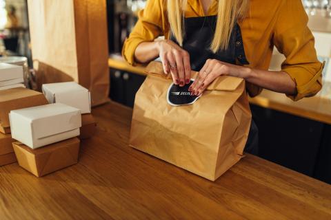 person folding bag at a takeout windwo