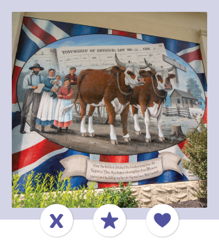 Photograph of a painted mural showcasing a family of five standing behind two brown cows, with a deed for the Township of Arthur and a union jack pattern in the background. 