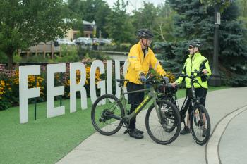 two people standing in front of 'fergus' sign with their bikes