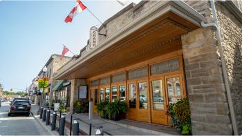 Outside of the Fergus Grand Theatre showcasing their wood doors and stained glass windows, with a sign for “The Fergus Grand Theatre” above the door. 