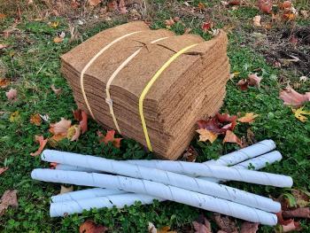 A bundle of mulch mats and rodent guards laid on grass