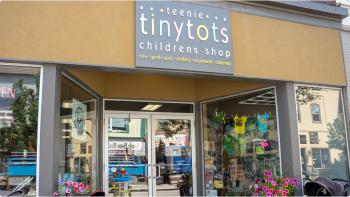 The front entrance to the shop "Tiny Tots" with lots of childrens items for sale out front.