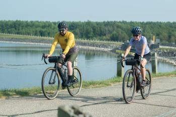 man and women biking down path by river