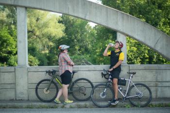 two bikers on bridge drinking water