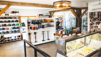 Image of the interior of a bike shop with bright white walls and shelving showcasing bike helmets and cycling accessories. 