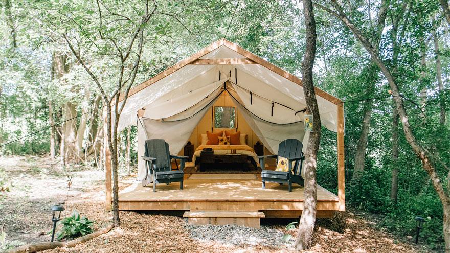 A beautifully decorated wooden framed yurt sits nestled in the forest