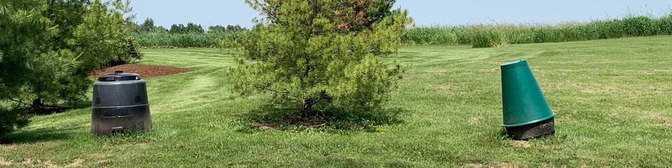 Two types of compost bins in a grassy area