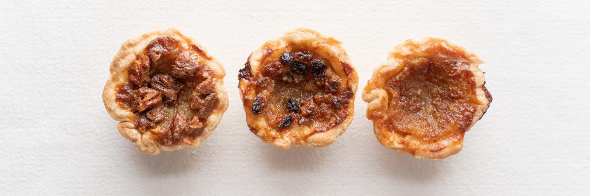 three flaky golden butter tarts lined in a row